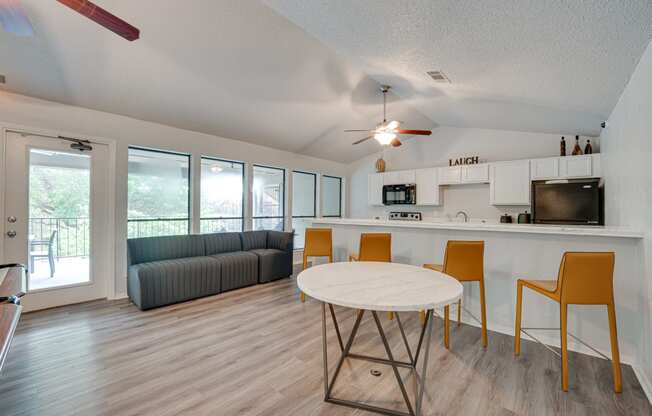 a living room with a round table and a kitchen with a couch