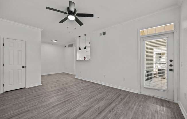 a living room with white walls and a ceiling fan