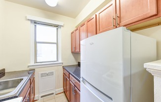 kitchen with wood cabinetry, electric range, refrigerator, and window at eddystone apartments in washington dc