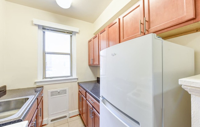 kitchen with wood cabinetry, electric range, refrigerator, and window at eddystone apartments in washington dc