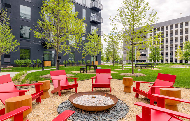 a courtyard with red chairs and a fire pit