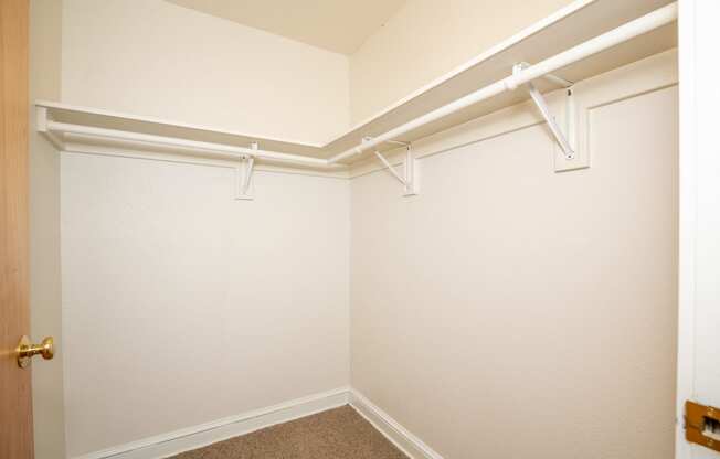 an empty closet with white walls and white hangers