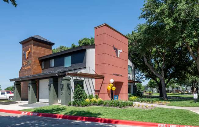 fusion Fort Worth leasing office with modern siding and awnings, green lawn, and large trees