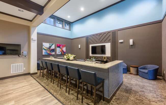 a long bar with blue chairs in a room with a television