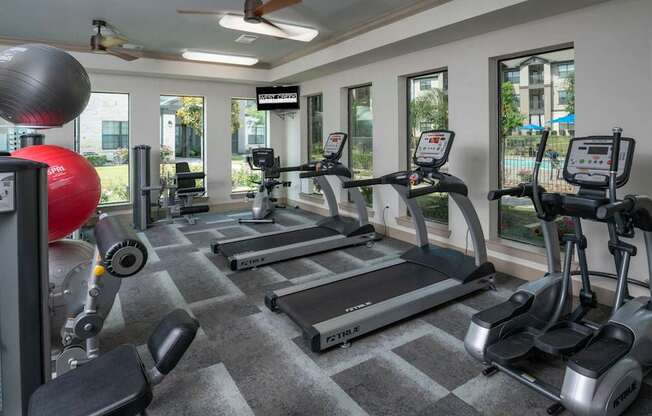 A gym with treadmills, elliptical machines, and a weight machine.