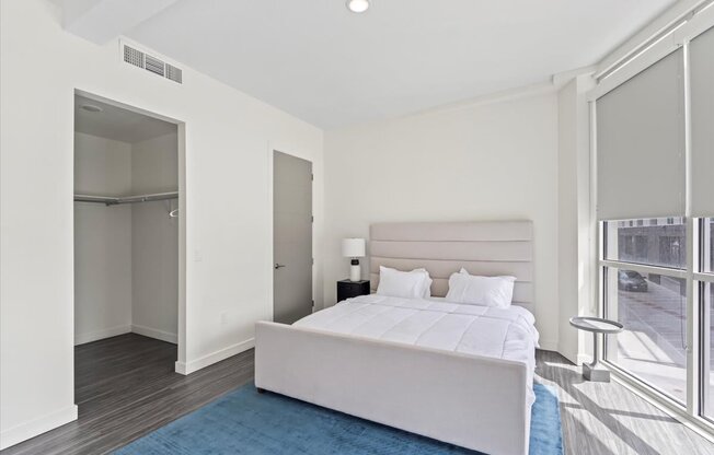 A bedroom with a large bed and a blue rug.