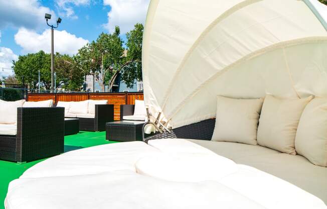 an outdoor lounge with a white bed on a green turf
