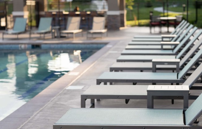 a row of lounge chairs next to a pool at The Clearing at ONE28, Olathe, 66062