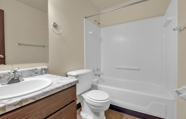A white toilet sits next to a white bathtub in a bathroom.