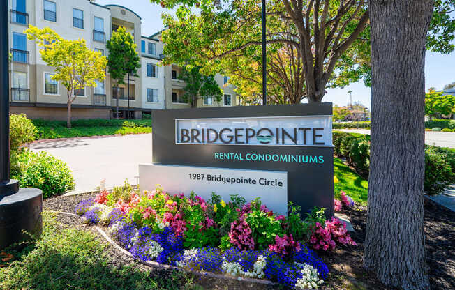 A sign for Bridgepointe Rental Condominiums stands in front of a building.