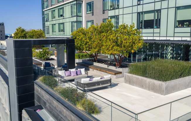 A modern outdoor seating area with a concrete structure and purple cushioned chairs.