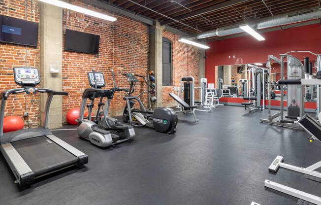 a gym with weights and cardio equipment in a brick wall