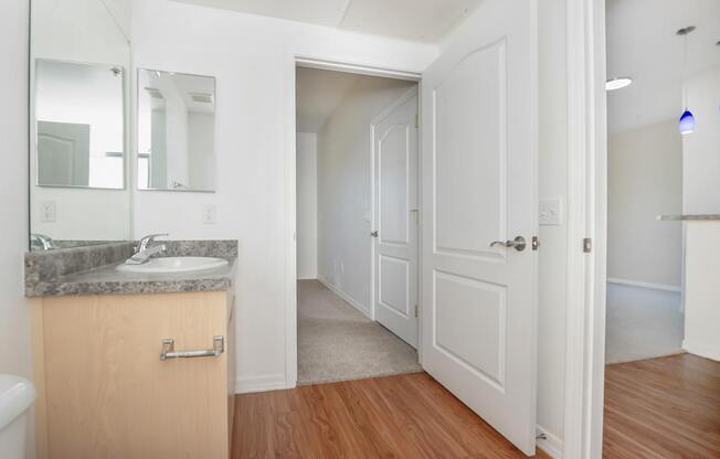 A bathroom with a sink, mirror, and wooden floors.