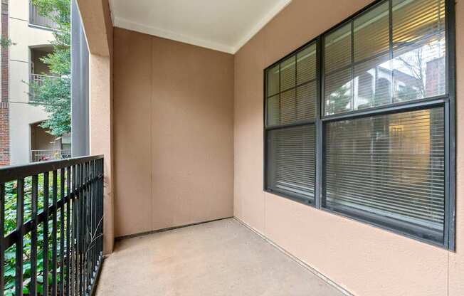 A balcony with black railings and a large window with blinds.