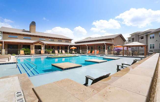 A large outdoor swimming pool with a diving board and a building in the background.