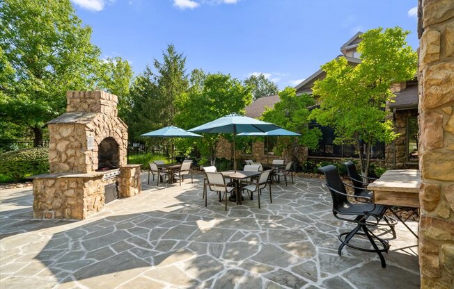 A patio with a stone fireplace and chairs.