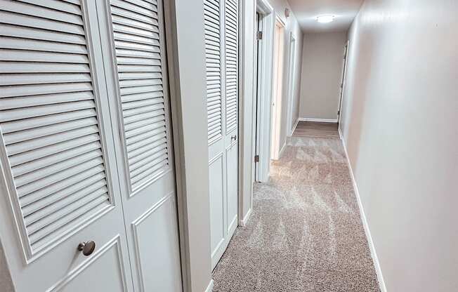 A long hallway with white doors and carpeted floors.