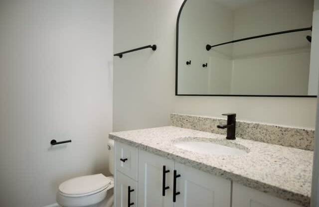 A bathroom with a toilet, sink, and mirror.