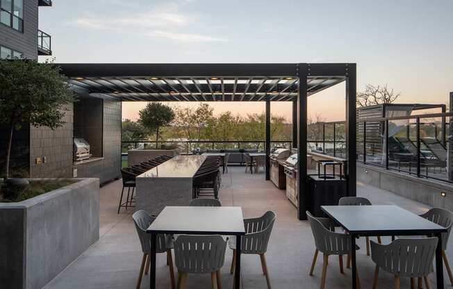 A patio with tables and chairs is set up under a pergola.