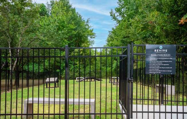 a gate to a park with benches and trees