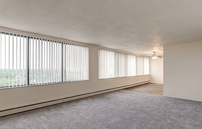 A room with a carpeted floor and a window with blinds.