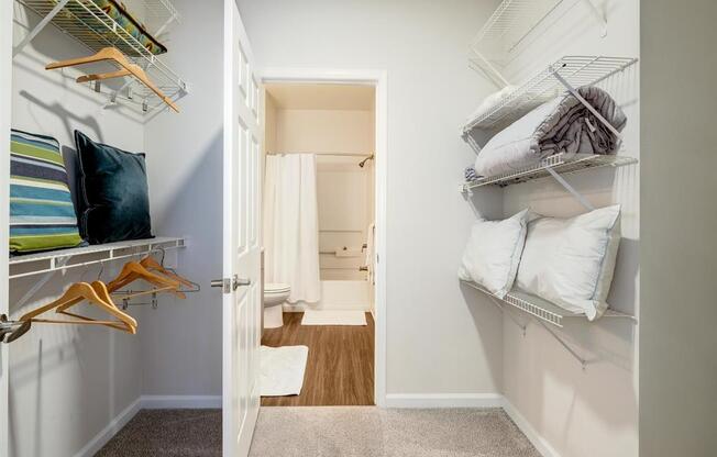 a closet with shelves and pillows and a door to a bathroom