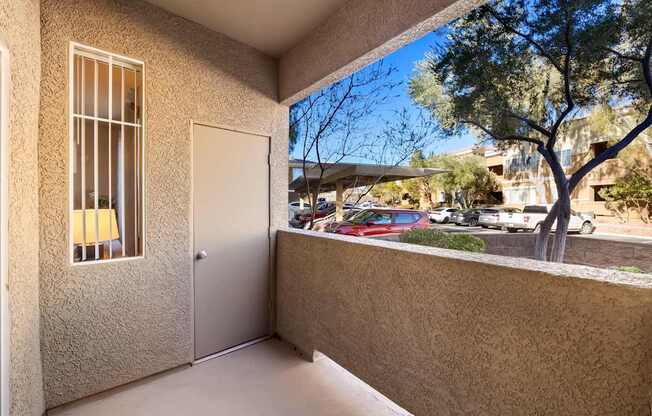 A balcony with a view of a parking lot and trees. at The Fairways by Picerne Apartments, Nevada, 89141