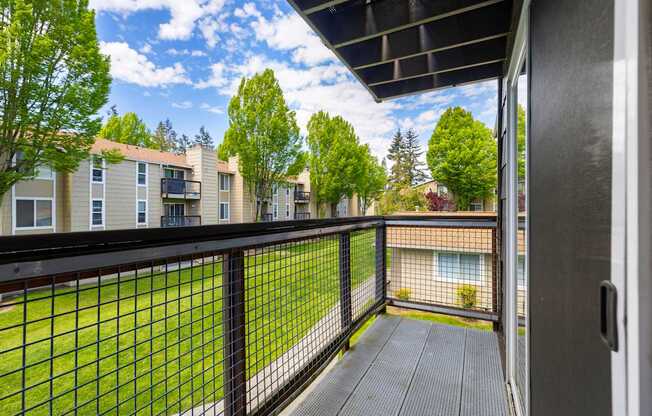 A balcony with a black railing and a view of apartment buildings.