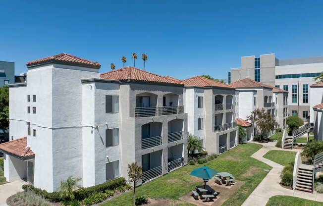 A white building with red tile roofs and a green lawn in front.