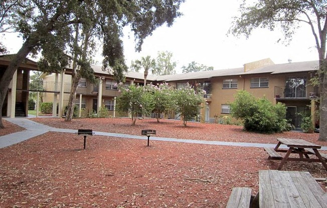 a courtyard with picnic tables and benches in front of an apartment building