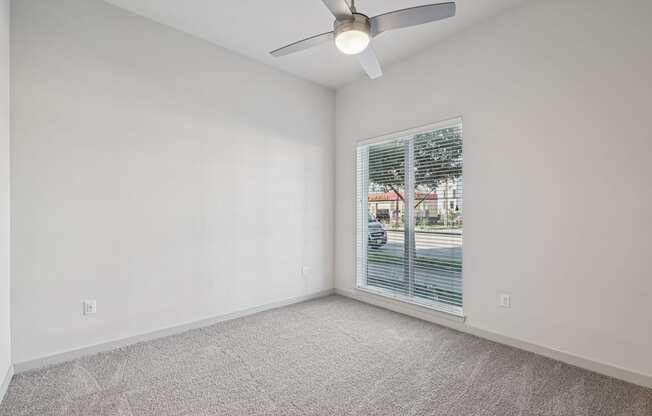 A room with a ceiling fan and carpeted floor.