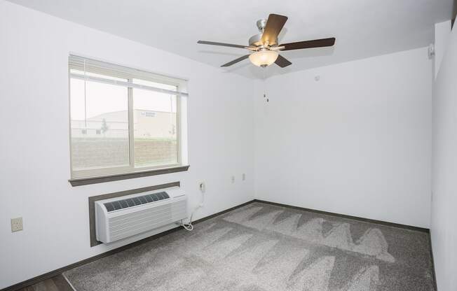 an empty room with a ceiling fan and a window