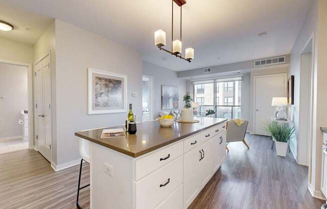 A kitchen with a large island and a dining area in the background.
