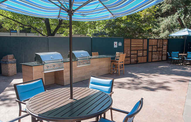 A table and chairs set up under a blue umbrella.