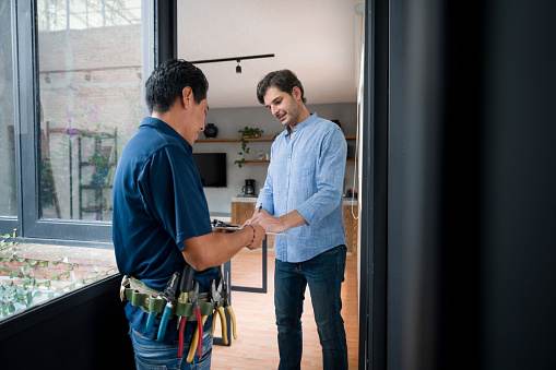 A man in a blue shirt is shaking hands with another man in a light blue shirt.