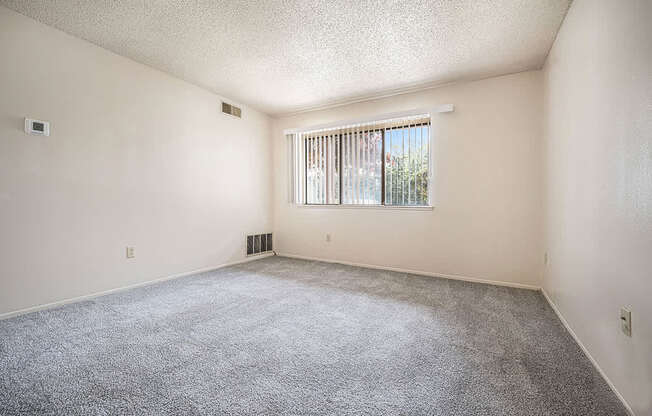 A garden style living room with a carpeted floor and a window with blinds at Seville Apartments, Michigan
