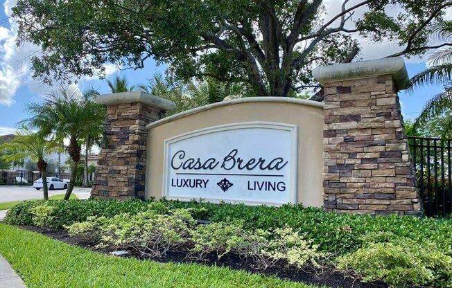 A sign for Casa Brera Luxury Living is displayed in front of a landscaped area.