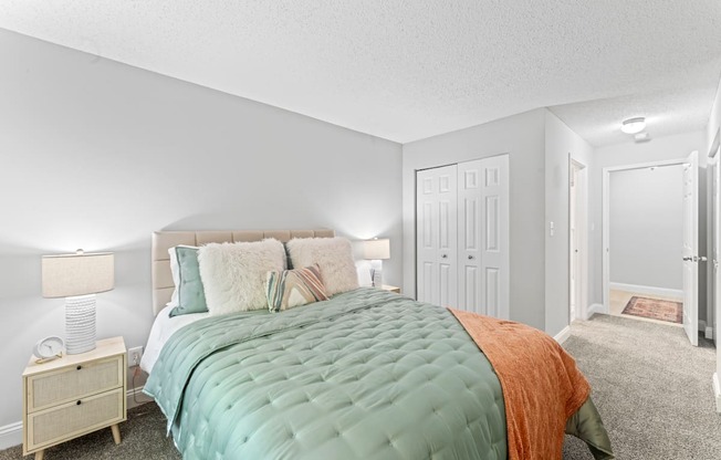 A bedroom with a large bed and a nightstand with a lamp.