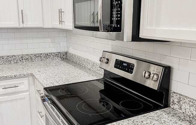 A kitchen with a black stove top oven and white cabinets.
