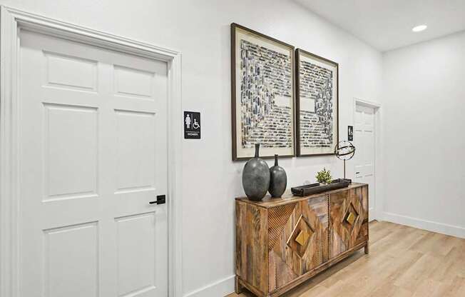 A white door with a black sign on it and a wooden cabinet with a plant on top.