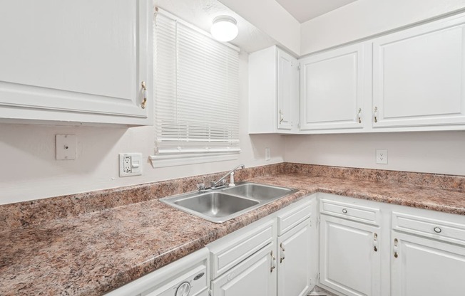 A kitchen with white cabinets and a granite countertop.