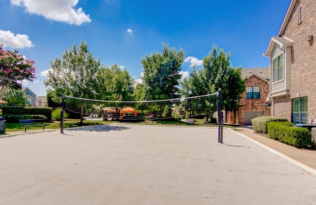 View of Sand Volleyball Court, Showing Net, Benches, and Building Exteriors at Enclave on Golden Triangle Apartments