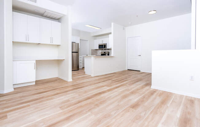 A kitchen area with white cabinets and a wooden floor.