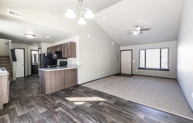 A spacious living room with a kitchen area in the background.