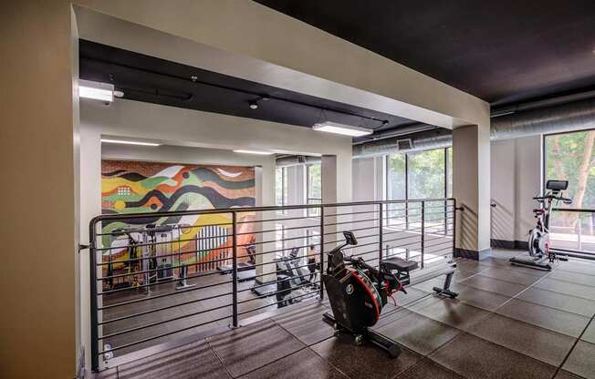 A room with a mural on the wall and exercise equipment.