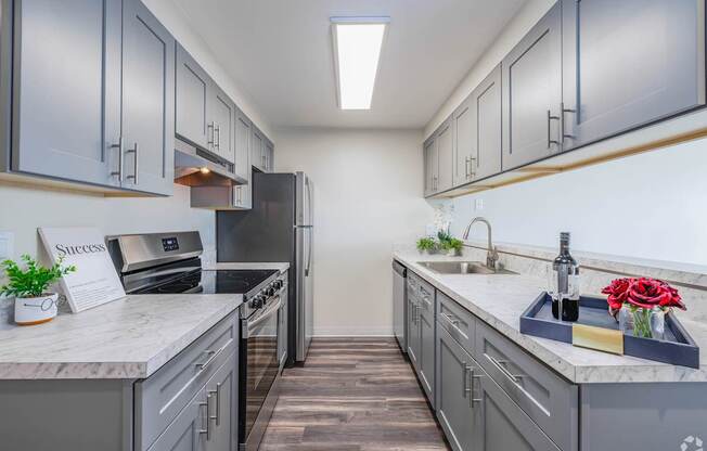 A kitchen with grey cabinets and a white countertop.