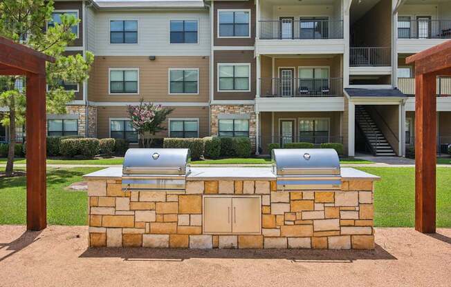 A stone wall with two grills on top of it.