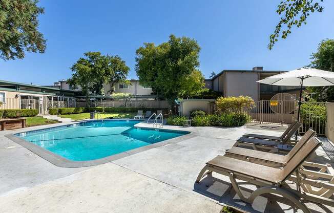 a swimming pool and patio with chairs and an umbrella