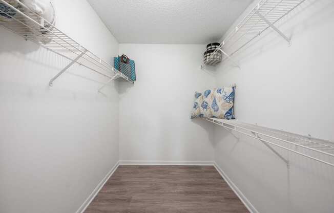 a spacious room with white walls and two shelves on the wall and a closet with