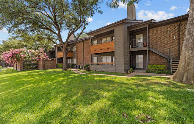 A modern house with a large front yard and a tree with pink flowers.